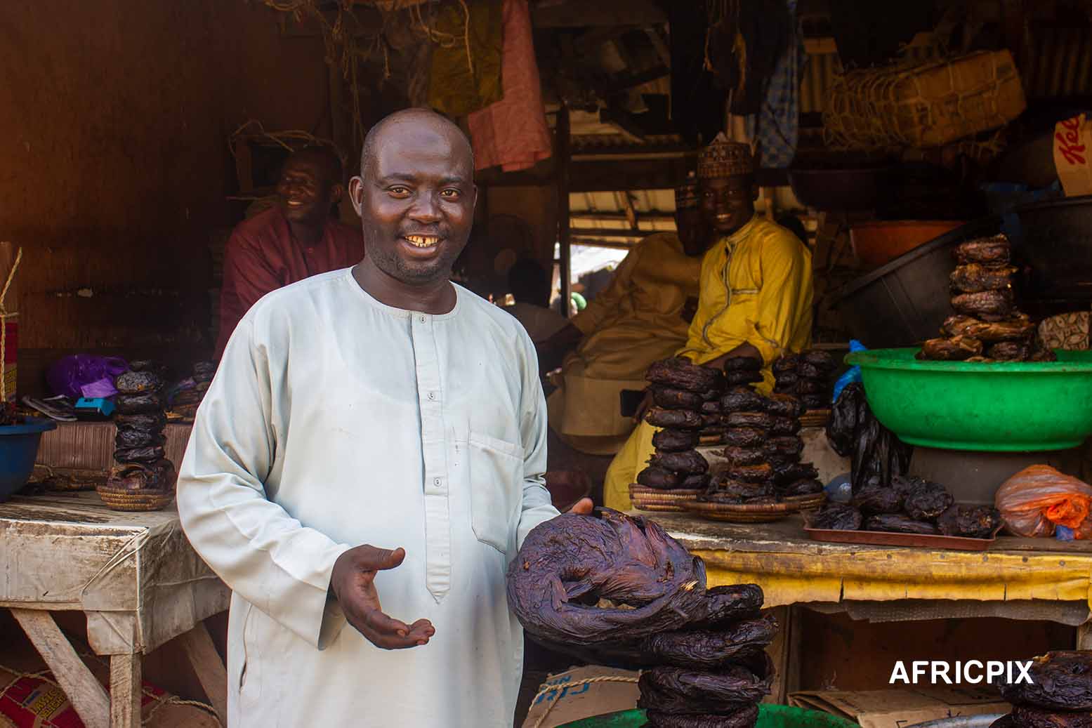 Nigeria Market Man In Front of Shop Holding Fish